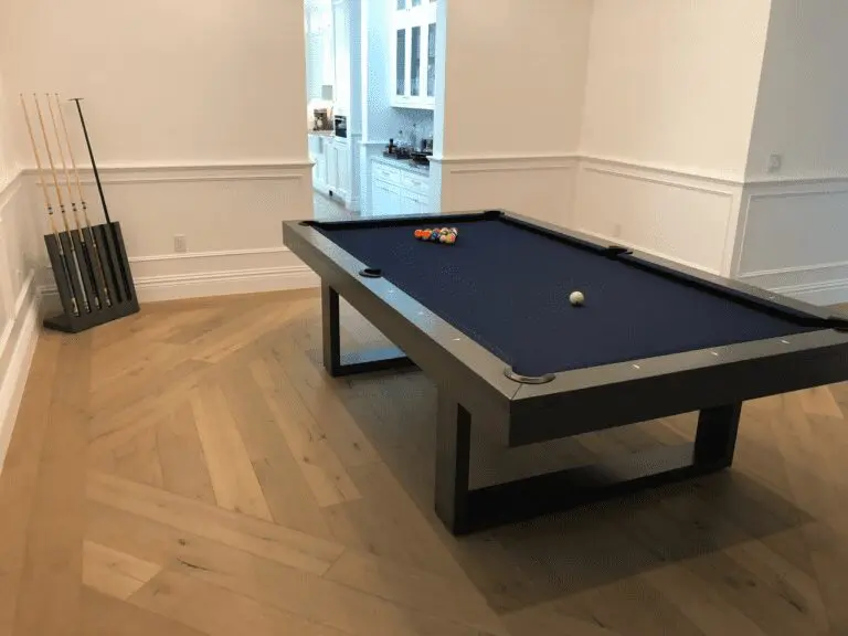A pool table in a white room next to a kitchen